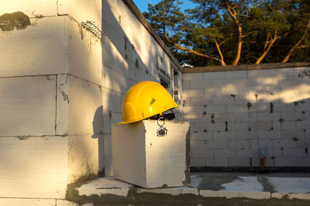 Construction yellow hardhat and key to house on window of housing made of blocks of porous concrete. Turnkey construction, future home, engineering, building. Work safety. Copy spaceの写真素材