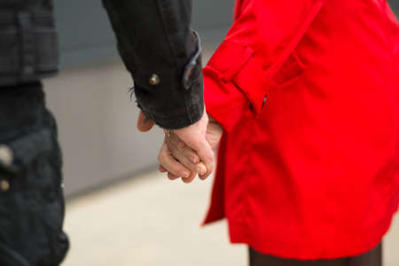 A man and a woman hold hands as a sign of love and support, together and forever - hands close-up. Relationships, a couple in love, a date, Valentine's day.の写真素材