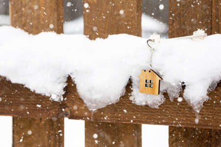 Key to the house on a wooden fence in winter in the snow. A gift for New Year, Christmas. Building, design, project, moving to new house, mortgage, rent and purchase real estate. Copy spaceの写真素材