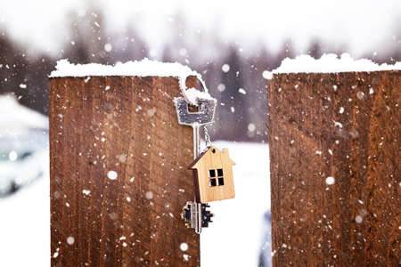 Key to the house on a wooden fence in winter in the snow. A gift for New Year, Christmas. Building, design, project, moving to new house, mortgage, rent and purchase real estate. Copy spaceの写真素材