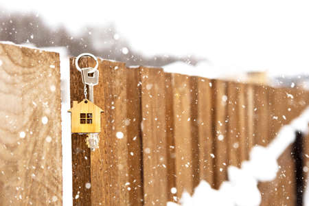 Key to the house on a wooden fence in winter in the snow. A gift for New Year, Christmas. Building, design, project, moving to new house, mortgage, rent and purchase real estate. Copy spaceの写真素材