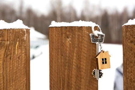 Key to the house on a wooden fence in winter in the snow. A gift for New Year, Christmas. Building, design, project, moving to new house, mortgage, rent and purchase real estate. Copy spaceの写真素材