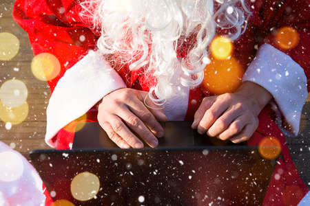 Santa Claus with a laptop and a gift in his hand. Order gifts for Christmas and new year through the online store. Booking the services of an animator for the holidays.の写真素材