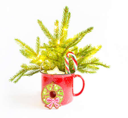 Christmas bouquet in a red mug made of live spruce and festive decorations and accessories, toys for the Christmas tree, sweets. New Year, festive mood, floristry on a white backgroundの写真素材