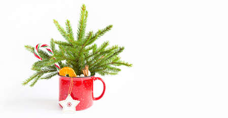 Christmas bouquet in a red mug made of live spruce and festive decorations and accessories, toys for the Christmas tree, sweets. New Year, festive mood, floristry on a white background with copy spaceの写真素材