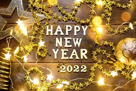 Happy New Year-wooden letters and the numbers 2022 on a festive background with sequins, stars, glitter, lights of garlands. Greetings, postcard. Calendar, coverの写真素材