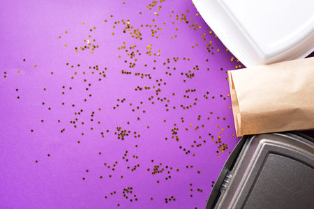 Food delivery service containers on a festive purple background with sequins. New year, christmas,...