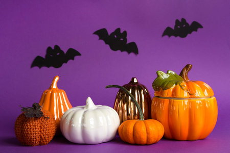 Halloween backgrounds of white, orange and gold pumpkins, spiders and black bats on a purple...