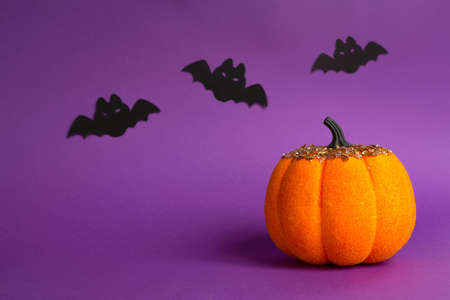 Halloween backgrounds of white, orange and gold pumpkins, spiders and black bats on a purple background with cobwebs and terrible scenery. Horror and a scary holiday with copy spaceの写真素材
