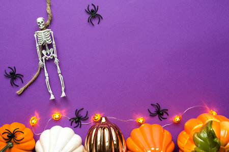Halloween layout of garland of skeleton on a rope, glowing Jack o Lantern, pumpkins, spiders on a...