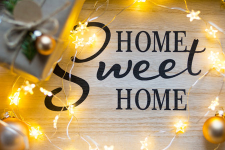 Home sweet home - the inscription on the board in the Christmas decor, fairy lights, a box with a gift for the new year. Background