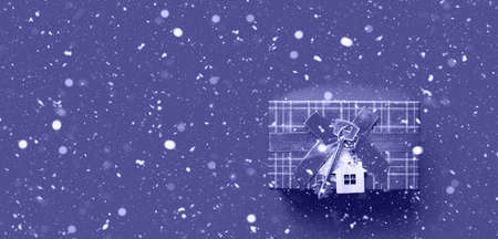 House key with keychain cottage. Happy New Year-red background with snow, gift, greeting card. Purchase, construction, relocation, mortgage. copy spaceの写真素材