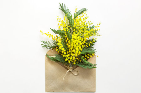 A yellow bouquet of mimosa and a gift box and a kraft paper bag. Greeting card for International...