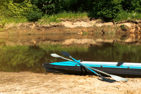 Tourist canoes with paddles stand on the river coast in summer on a water hike. Rafting on...