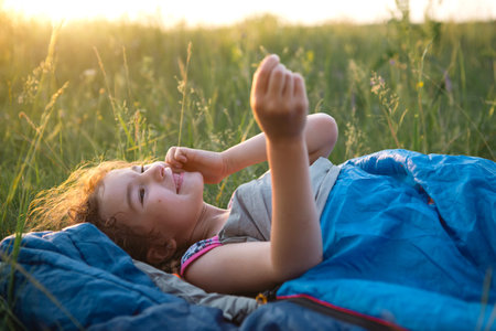 The girl is dissatisfied with scratching mosquito bites, child sleeps in a sleeping bag on the grass...