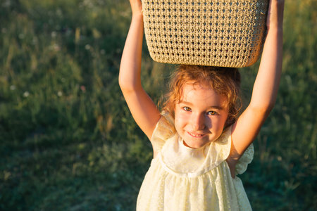 Summer portrait of a girl with a basket on her head - harvest in the garden, picking fruits and berries, gifts of natureの写真素材