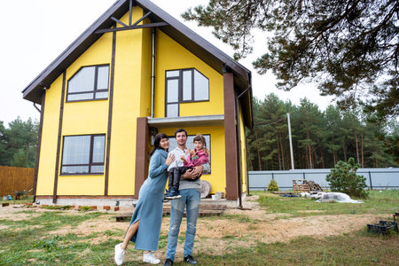 Happy family in the yard of an unfinished house - purchase of a cottage, mortgage, loan, relocation, construction