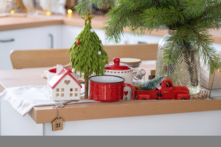 Key to the house on cozy home with Christmas decor on table of festive kitchen. Gift for New Year. Building, design, project, moving to new house, mortgage, rent and purchase real estateの写真素材