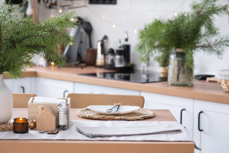 Festive Christmas decor in white kitchen, festive breakfast, white scandi interior. The figure of a cozy house ion set table. New Year, mood, cozy home. copy spaceの写真素材