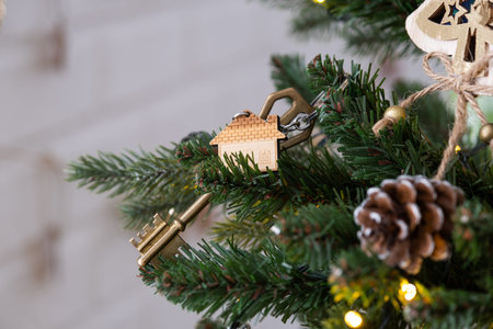 Key to the house with a keychain is hanging on the Christmas tree. A gift for New Year, Christmas....