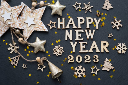 Happy New Year-wooden letters and the numbers 2023 on festive black background with sequins, stars,...