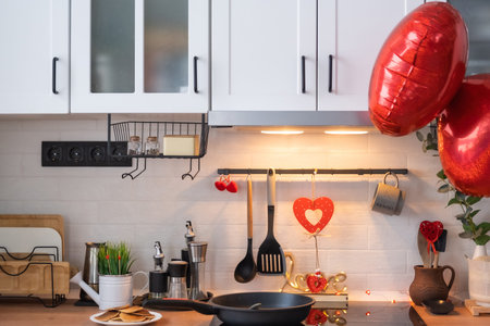 The interior of the kitchen in the house is decorated with red hearts for Valentine's Day. Decor on...