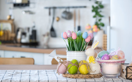 Easter decoration of colorful eggs in a basket and a rabbit on the kitchen table in a rustic style. Festive interior of a country houseの写真素材