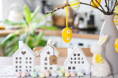 Key to house of cozy home with Easter decor with rabbit and eggs on table of kitchen. Building, design, project, moving to new house, mortgage, insurance, rent and purchase real estateの写真素材