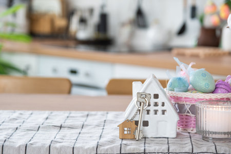 Key to house of cozy home with Easter decor with rabbit and eggs on table of kitchen. Building, design, project, moving to new house, mortgage, insurance, rent and purchase real estateの写真素材