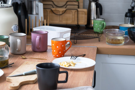 A mess in the kitchen, dirty dishes on the table, scattered things, unsanitary conditions. The dishwasher is full, the kitchen is untidy, everyday lifeの写真素材
