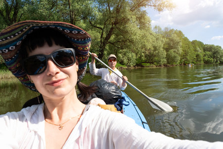 Man and woman couple, baby is sleeping, selfies are happy in family kayak trip rowing boat on the river, water hike, a summer adventure. Eco-friendly and extreme tourism, active and healthy lifestyleの写真素材