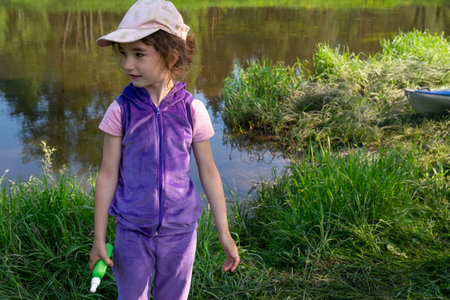 Girl sprays mosquito spray on the skin in nature that bite her hands and feet. Protection from insect bites, repellent safe for children. Outdoor recreation, against allergies. summer timeの写真素材