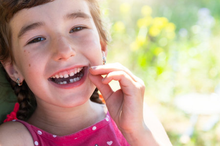 Toothless happy smile of a girl with a fallen lower milk tooth close-up. Changing teeth to molars in childhoodの写真素材