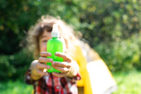 Girl uses a remedy for mosquitoes and biting insects in nature. Protection of skin from tick bites, gadflies, blood-sucking pests, means for children without allergens for outdoor camping. in focusの写真素材