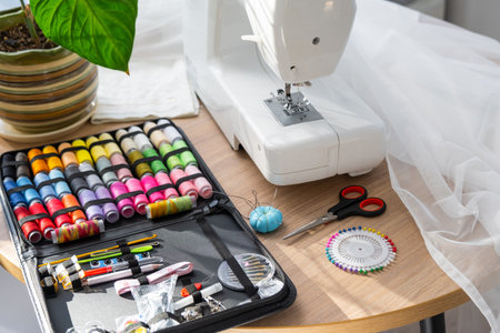 Sewing layout with multicolored spools of thread close-up, needles, electric sewing machine. Filling the thread into the sewing needle, adjusting the tension. hobby, home businessの写真素材