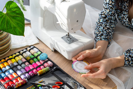 Woman hand close up sews tulle on electric sewing machine. Filling the thread into the sewing...