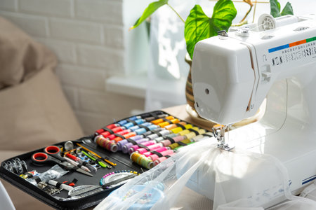 Sewing layout with multicolored spools of thread close-up, needles, electric sewing machine. Filling the thread into the sewing needle, adjusting the tension. hobby, home businessの写真素材