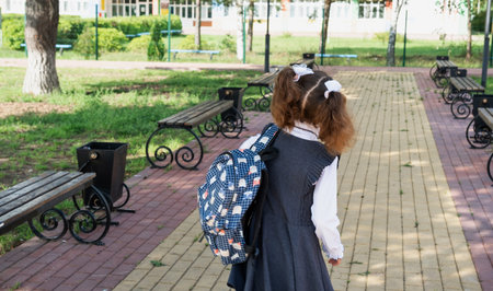 Pupil with backpack and in a school uniform in school yard back to the frame. Back to school, September 1. A happy student. Primary education, elementary class. Road to life, to knowledgeの写真素材