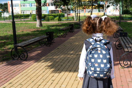 Pupil with backpack and in a school uniform in school yard back to the frame. Back to school,...