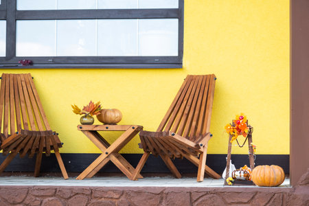 Autumn decor on the porch of the house outside in the yard of pumpkin, lantern, garlands, hats, jack lantern. Halloween party, autumn mood, Harvest festivalの写真素材