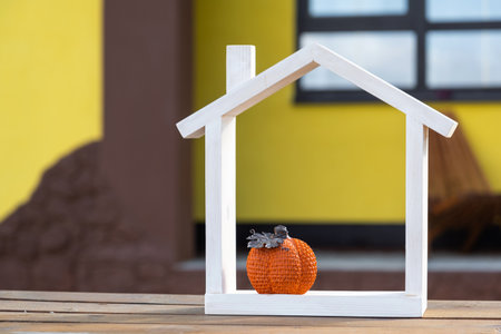 Autumn decor on porch of yellow house outside of pumpkin, lantern, garlands and figure of home and key. Halloween party, autumn mood, Harvest festival, real estate, insurance, mortgageの写真素材