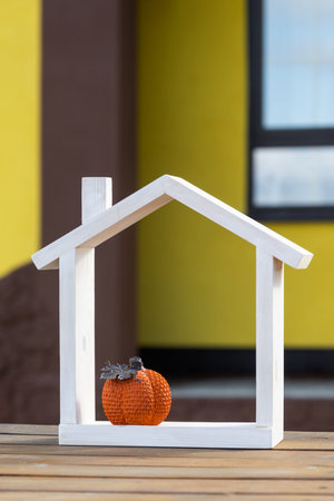 Autumn decor on porch of yellow house outside of pumpkin, lantern, garlands and figure of home and key. Halloween party, autumn mood, Harvest festival, real estate, insurance, mortgageの写真素材