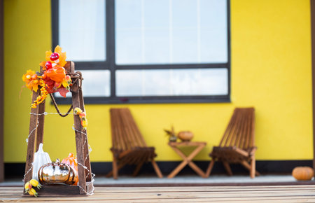 Autumn decor on the porch of the house outside in the yard of pumpkin, lantern, garlands, hats, jack lantern. Halloween party, autumn mood, Harvest festivalの写真素材