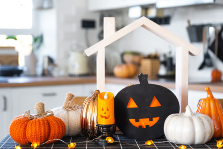 Decor of white classic kitchen with pumpkins, garlands, jack latern for Halloween and harvest with figurine of house. Autumn mood in home interior, modern loft style. real estate, insurance, mortgageの写真素材