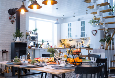Festive interior of house is decorated for Christmas and New Year in loft style with black stove, fireplace, Christmas tree. Warm studio room with set table, burning wood, cozy and heating of homeの写真素材