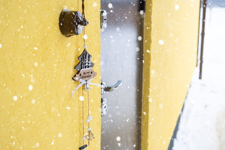 A Christmas tree-shaped pendant with the inscription merry Christmas hangs on the front door of the...