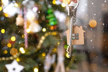 Key to the house with a keychain is hanging on the Christmas tree. A gift for New Year, Christmas....