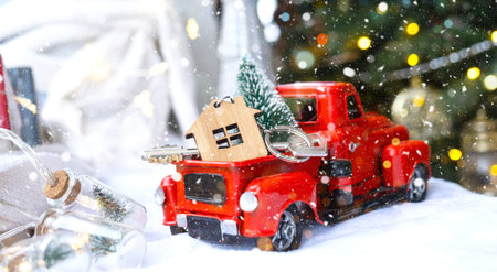 Red retro car with a Christmas tree decorates with the house key in the pickup truck for Christmas....