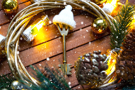 Key to house with keychain on cozy brown wooden background with Christmas decor layout. Gift for New...