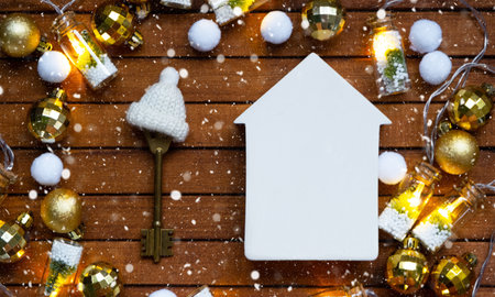 Key to house with a keychain tiny home on wooden background with Christmas decor layout. Gift for New Year, Christmas. Building, project, moving to new house, mortgage, rent and purchase real estateの写真素材